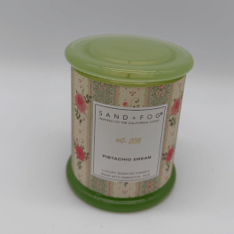 A floral-patterned scented candle in a green tin container