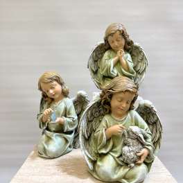 Three angel figurines in pale green robes sit on a stone base.