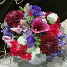 Bouquet of purple, red, and pink flowers in a white vase