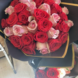 Bouquet of red and pale pink roses wrapped in black paper