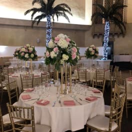 Tall floral centerpieces on round banquet tables in a reception hall