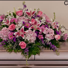 Pink and white funeral spray with roses and lilies on a casket