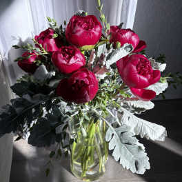 Bouquet of deep pink peonies in a clear glass vase