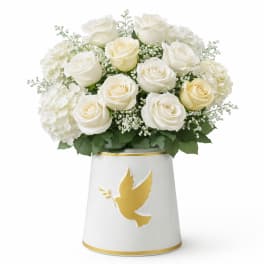 White roses and hydrangeas in a white vase with a gold dove emblem