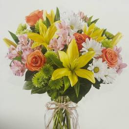 Bouquet of yellow lilies, orange roses, and white daisies in a glass vase