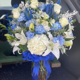 Blue and white bouquet with roses, lilies, and hydrangea tied with a blue ribbon