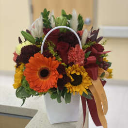 Mixed bouquet with sunflowers, roses, and a white handled container