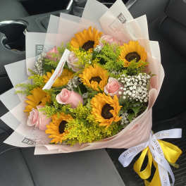 Bouquet of sunflowers and pink roses wrapped in pale paper