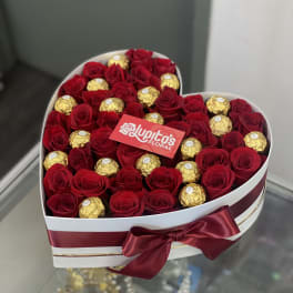 Heart-shaped box of red roses and gold-wrapped chocolates with a satin bow