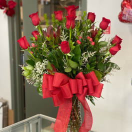 Bouquet of red roses in a clear glass vase with a large red ribbon