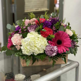 Mixed bouquet in a wooden box with pink, purple, white, and red flowers