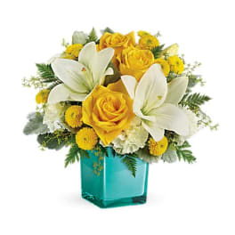 Yellow roses and white lilies in a turquoise glass vase