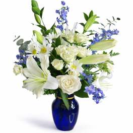 White lilies, roses, and blue flowers in a cobalt vase