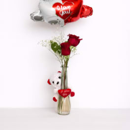 Red roses in a vase with teddy bear balloons and a plush bear