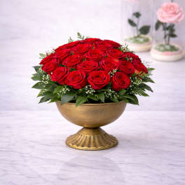 Red rose arrangement in a gold pedestal bowl