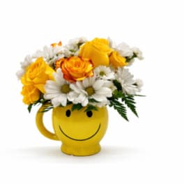 Yellow smiley-face mug filled with yellow roses and white daisies
