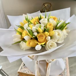 Bouquet of yellow and white roses with white tulips wrapped in white paper