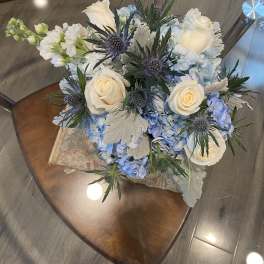 Bouquet of white roses and blue hydrangeas with spiky thistle flowers
