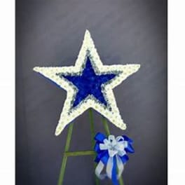 Blue and white star-shaped floral tribute on a stand with a ribbon bow