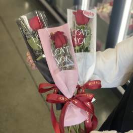 Three wrapped red rose bouquets with ribbons and "LOVE YOU" sleeves