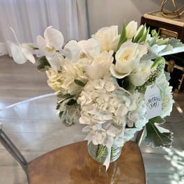 White floral bouquet in a glass vase with a Mother's Day tag