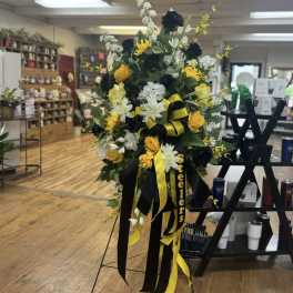 Tall black, white, and yellow funeral spray on an easel with ribbons