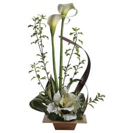 White calla lilies and green foliage in a modern wooden container