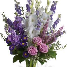 Purple and white floral arrangement in a clear glass vase