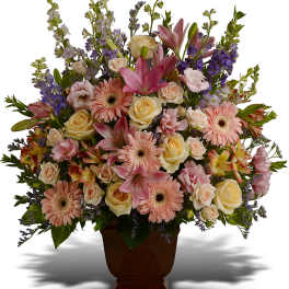 Mixed bouquet of pink lilies, roses, and gerbera daisies in a brown vase
