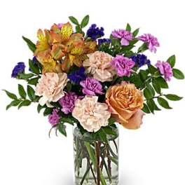 Mixed bouquet of roses, carnations, and purple filler flowers in a glass vase