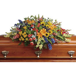 Colorful casket spray with mixed flowers on a wooden coffin