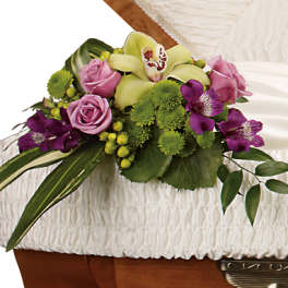 Floral casket spray with pink roses, green orchids, and purple blooms