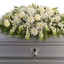 White floral casket spray with mixed blooms on a gray casket