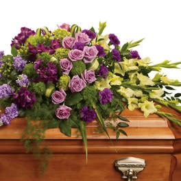 Purple, pink, and yellow flowers arranged on a wooden casket