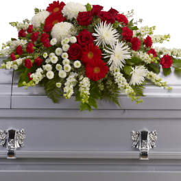 Red, white, and green floral spray on a silver casket