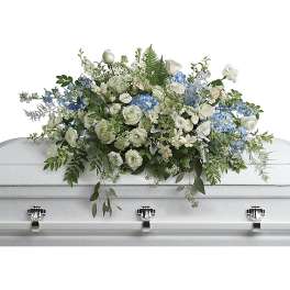 White and blue floral casket spray on a white casket