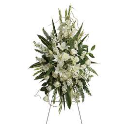 White floral standing spray on an easel with lilies and roses