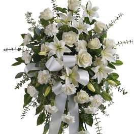 White floral standing spray on an easel with ribbon