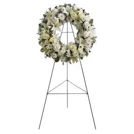 White floral wreath on a black standing easel