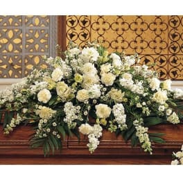 Large white and cream floral casket spray arranged in an elongated cascade