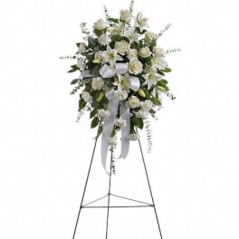 White floral standing spray on a metal easel with ribbon