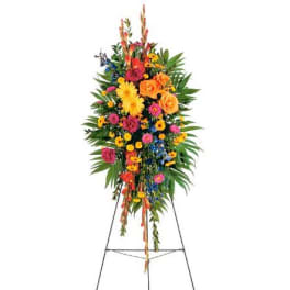 Tall standing spray of bright yellow, orange, pink, and blue flowers on a metal easel
