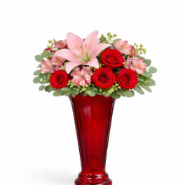 Red roses and pink lilies arranged in a tall red vase