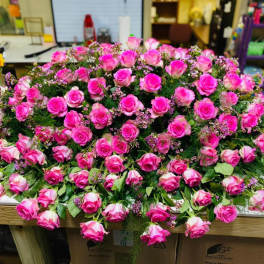 Large mound of pink roses with small filler flowers on a table