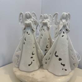 Three white ceramic angel figurines on a round base