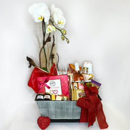 Gift basket with white orchids, chocolates, and a bottle of wine