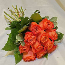 Bouquet of orange roses with green foliage on white wrapping