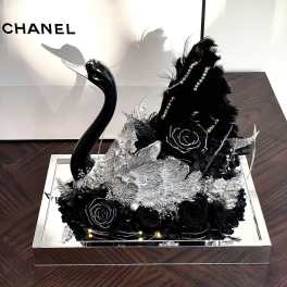 Black floral arrangement with a swan figurine in a mirrored tray