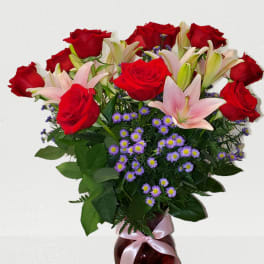 Red roses and pink lilies in a vase with a ribbon