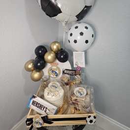 Soccer-themed balloon and dessert gift tray with a cake and chocolates
